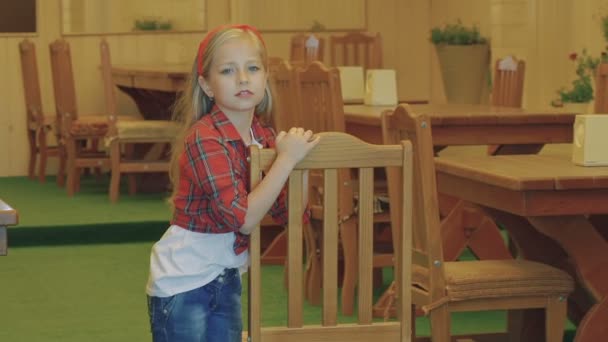 Cute little Blondynka pozowanie w pobliżu krzesło. Powoli — Wideo stockowe