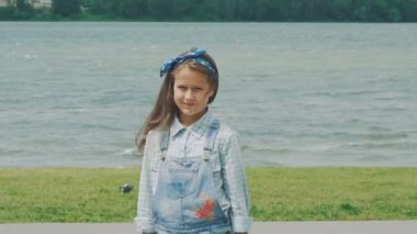 Küçük esmer kameraya sahilde yürüyor. Yavaş yavaş