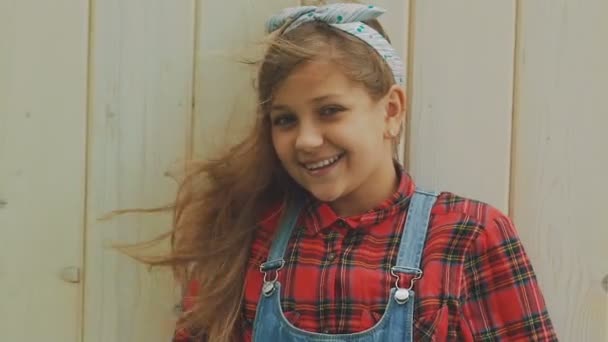 Πορτραίτο του ευτυχής κορίτσι με το φύσηγμα μαλλιά χαμογελά στη φωτογραφική μηχανή. Σιγά-σιγά — Αρχείο Βίντεο