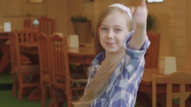 Sevimli küçük sarışın uzun saçları, atlar yukarı ve kamera gülümseyen dokunur. Yavaş yavaş