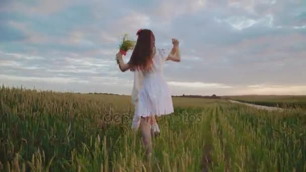 Dos chicas jóvenes en vestido bordado saltando en círculo en el trigo y regocijándose — Vídeo de stock