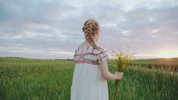 Nakış elbiseli genç sevimli kız buğday buket çiçek ile içeri girer — Stok video