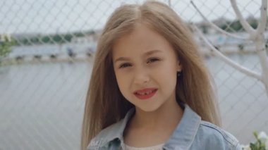 Gülümseyen ve 4 k kameraya bakarak uzun saçlı akıllı küçük kadın modeli