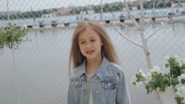 Gülümseyen ve 4 k kameraya bakarak uzun saçlı akıllı küçük kadın modeli