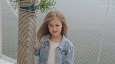 Gülümseyen ve 4 k kameraya bakarak uzun saçlı akıllı küçük kadın modeli