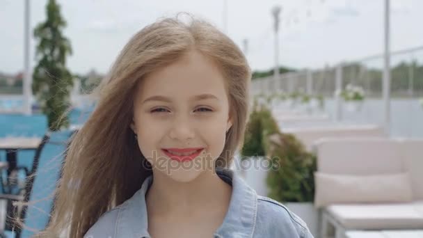 Pequeña modelo femenina inteligente con el pelo largo sonriendo y mirando a la cámara 4K — Vídeo de stock