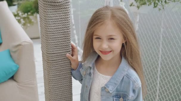 Slimme kleine vrouwelijke model met lange haren glimlachen en kijken naar camera 4k — Stockvideo