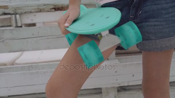Gorgeous little girl on a beachfront promenade posing, holding her skateboard — Stock Video