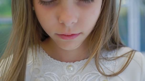 Schattig klein meisje met wilde bloemen kroon kijkt en knippert op de camera 4k — Stockvideo