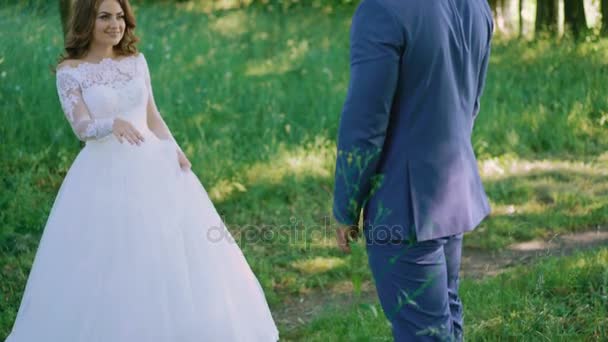 Gelukkige bruid en bruidegom poseren en omarmen in het groene woud 4k — Stockvideo