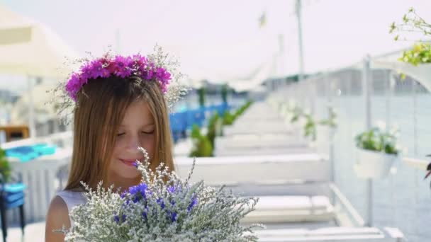 Feliz niña oliendo las flores y mirando la cámara en el bar. 4K — Vídeos de Stock