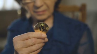 Yaşlı kadın portresi bir altın bitcoin elinde tutan kameraya