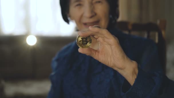 Retrato de anciana muestra un bitcoin de oro en la mano en la cámara — Vídeos de Stock