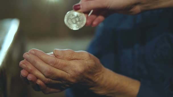 Young hand puting bitcoin into old wrinkled hands — Stock Video