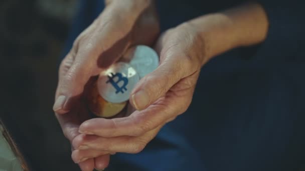 Wrinkled old female hands holding many golden and silver bitcoins — Stock Video