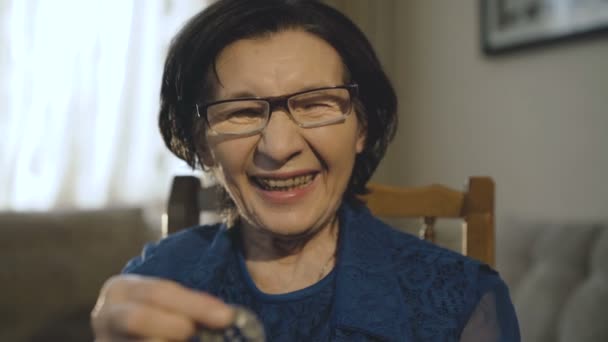 Happy old woman shows a silver bitcoin for camera and smiling — Stock Video