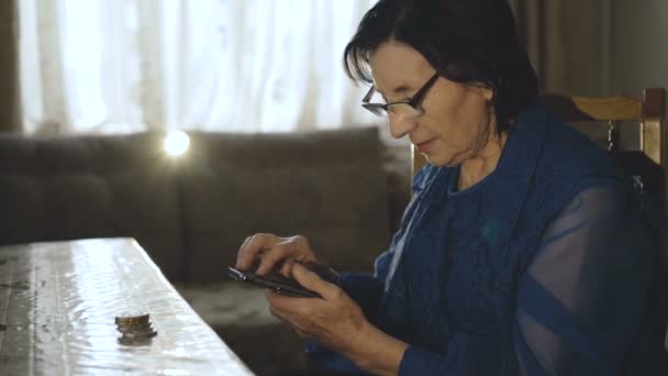 Old woman uses her bitcoin purse on the smartphone — Stock Video