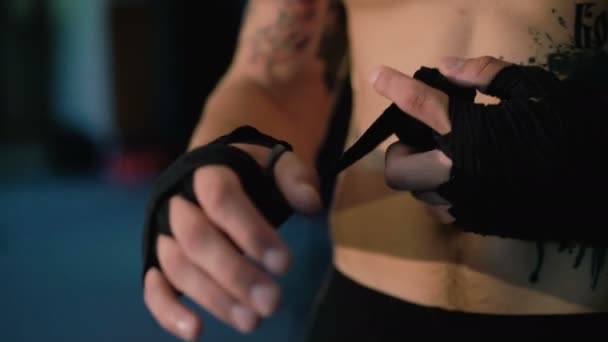 Luchador libre envuelve sus manos con una envoltura de mano negra antes del entrenamiento de lucha. 4K — Vídeo de stock