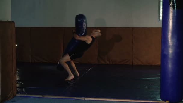 Sin pelo con coleta y tatuajes, entrenamiento de combate gratuito con saco de boxeo. 4K — Vídeo de stock