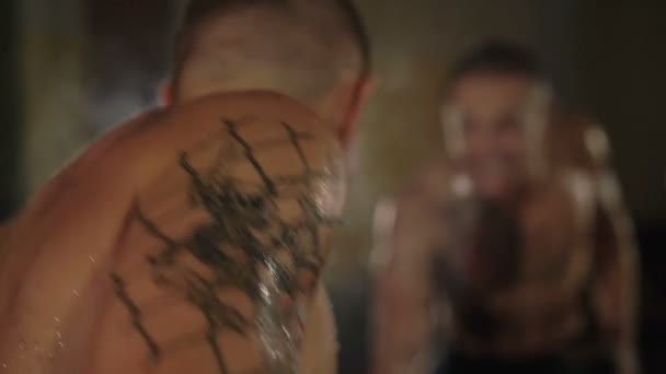 Sem pelos com tatuagens lutador livre levanta os halteres na frente do espelho. 4K — Vídeo de Stock