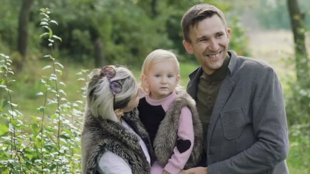 Porträt einer glücklich lächelnden Familie mit einem liebenswerten Kind in einem Park. langsam — Stockvideo