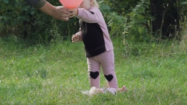 Padre le da a su pequeña hija globo, que sopla lejos. Despacio. — Vídeos de Stock