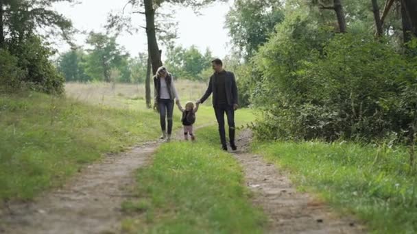 Família feliz caminha com seu pequeno filho sobre a natureza. Devagar. — Vídeo de Stock