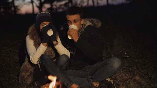 Romantic couple resting at bonfire, smiling, caressing, drinking tea — Stock Video