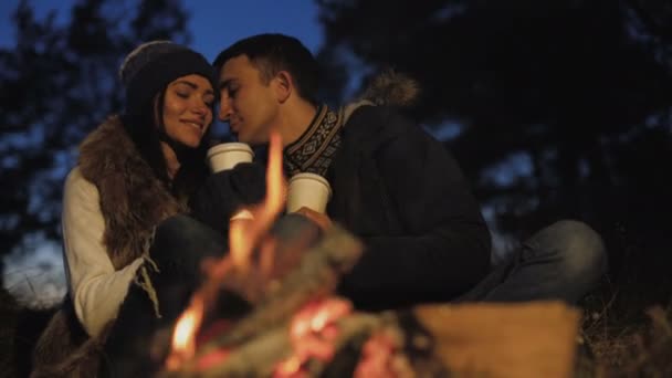 Romantische paar rust aan bonfire, glimlachen, zoenen en strelen — Stockvideo