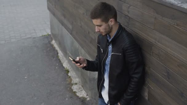 Stylowy mężczyzna przy użyciu smartfona o drewniany budynek 4k — Wideo stockowe