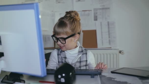 Симпатичная маленькая, умная школьница с компьютером и планшетом на рабочем месте. 4K — стоковое видео