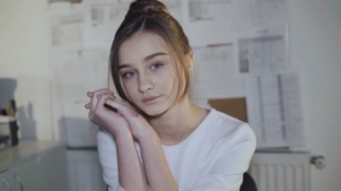 Sevimli kız işyerinde oturur, el ve kamera gülümsüyor üzerinde eğilir.