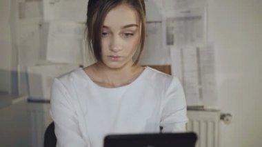 İşyerinde gülümseme ile tablet kullanan sakin genç kız. 4k