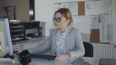 Gözlüklü genç office kız ofiste bilgisayar çalışır. 4k