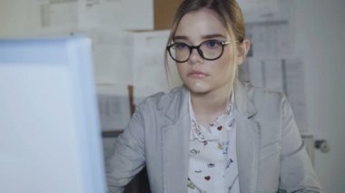 Gözlüklü genç office kız ofiste bilgisayar çalışır. 4k