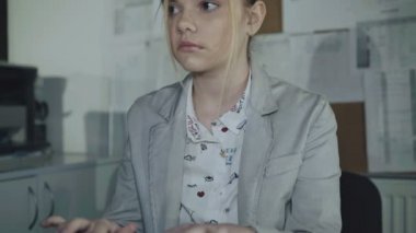 Genç kız klavyede yazarak ve Office kamera bakıyor. 4k