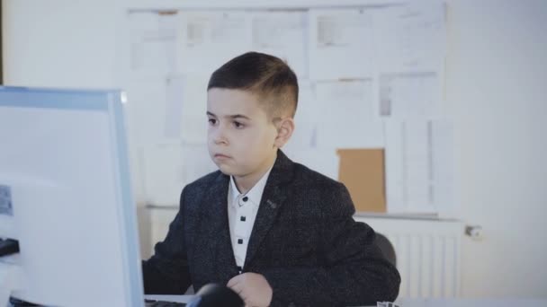 Маленький симпатичный мальчик работает с компьютером в офисе. 4K — стоковое видео