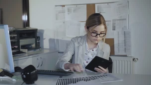 Das vielbeschäftigte Mädchen arbeitet im Büro mit Diagrammen, PC und Tablet. 4k — Stockvideo