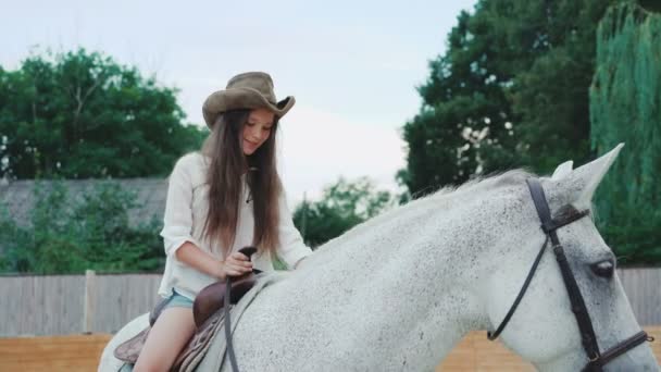 Jovem menina feliz posa em um cavalo muito branco na área. 4K — Vídeo de Stock