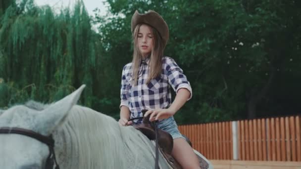 Ładna dziewczyna siedzi na koniu i uśmiecha się do kamery w rozdzielczości 4k — Wideo stockowe
