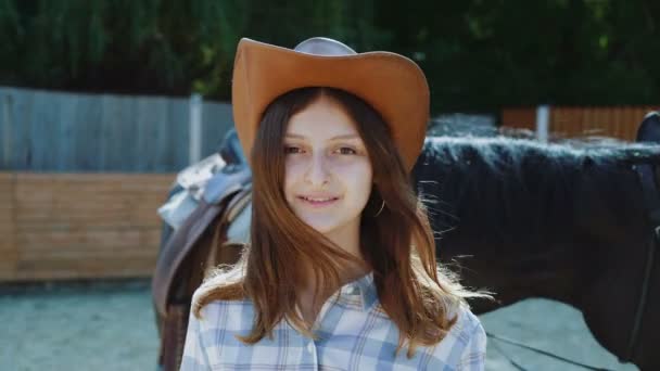 Retrato de una chica feliz e inteligente sonriendo a la cámara en el área del caballo. 4K — Vídeos de Stock