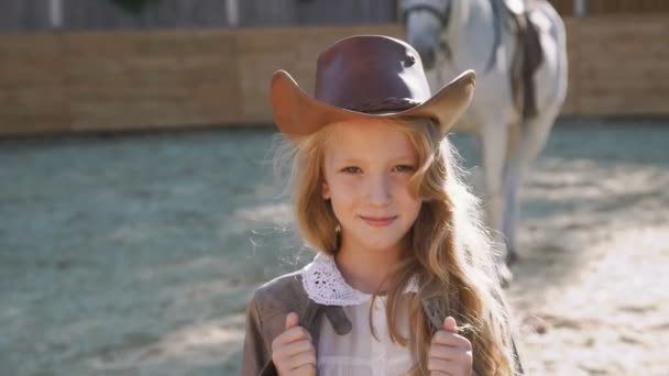 Retrato de uma menina feliz inteligente sorrindo para a câmera na área do cavalo. 4K — Vídeo de Stock