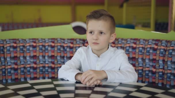 Jonge knappe jongen wachten in café met serieuze blik. 4k — Stockvideo