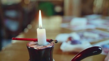 Kameradaki ahşap masada yanan beyaz mumlar.