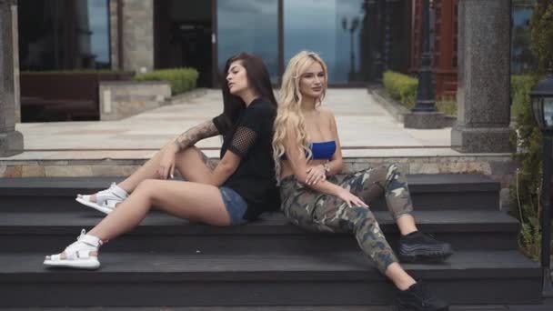 Leidenschaftliche Brünette und Blondine mit langen Haaren posiert auf Treppen im Haus — Stockvideo