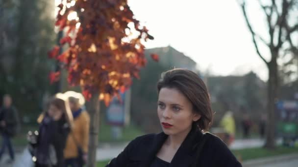 Thoughtful lady stands in poses on autumn street and looks aside — Stock Video