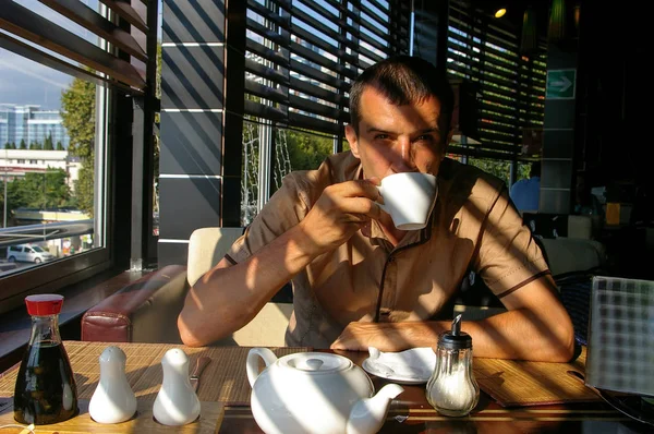 Joven bebiendo un café en el café. La sombra de la malla —  Fotos de Stock
