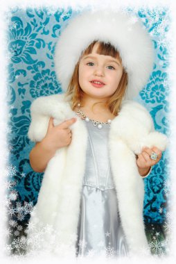 Kafasında tüylü beyaz şapkası olan güzel bir prenses elinde kar taneleri çerçevesinde kürk mantosundan bir tasma tutuyor. Yılbaşı konsepti.