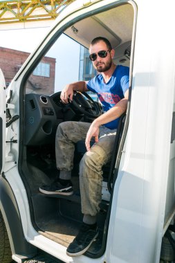 Bir adam kaputu açık bir kamyoneti tamir ediyor..