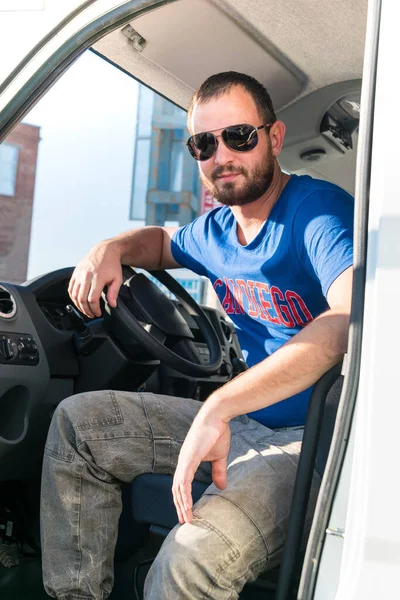 A man driver is repairing a truck with an open hood.